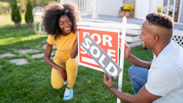 A couple putting up a sold sign over a for sale sign